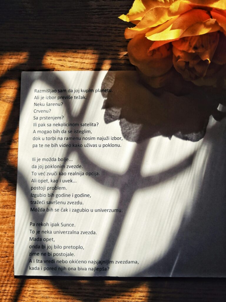 A page of poetry with artistic shadows next to vibrant yellow flowers.