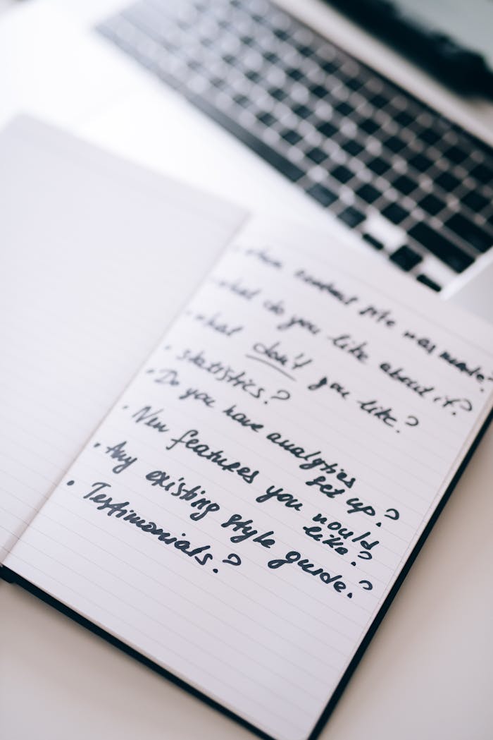 Open notebook with handwritten business notes beside a laptop, ideal for planning or strategy themes.
